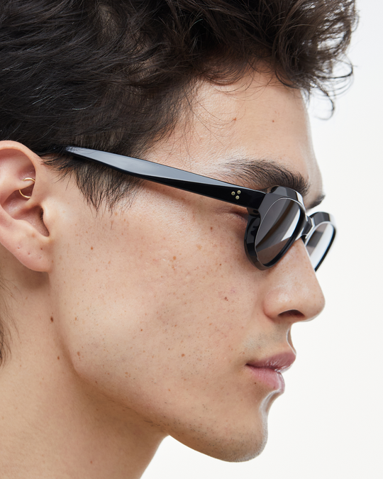 Man wearing Agaté black oval cat-eye sunglasses with black lenses, look 3
