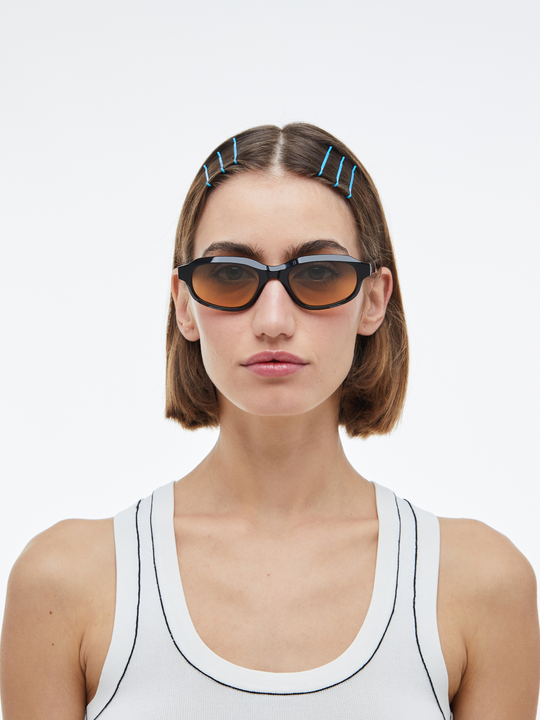 Woman wearing Agaté black oval cat-eye sunglasses with gradient orange-to-blue lenses