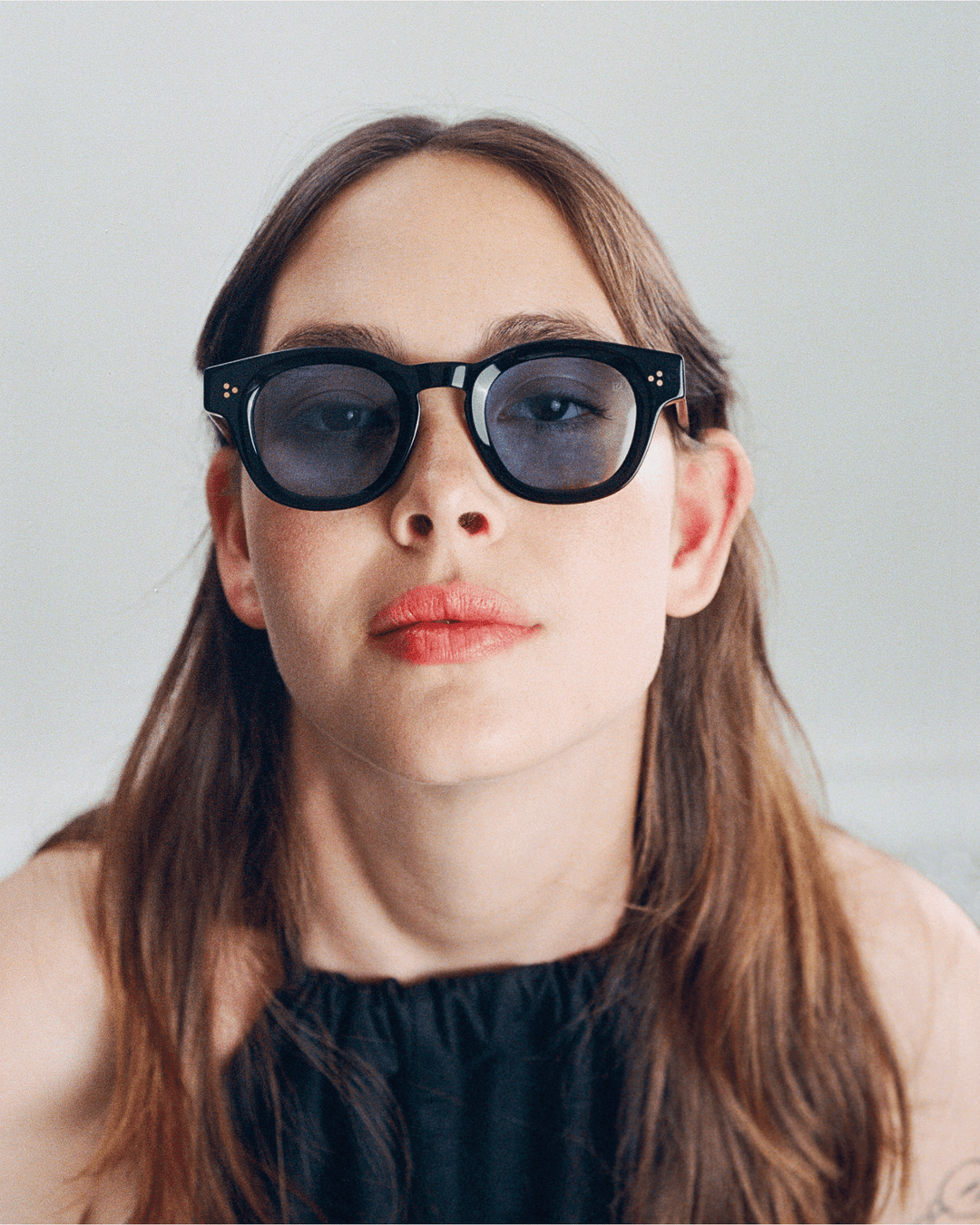 Woman wearing Coco black round sunglasses with light blue lenses