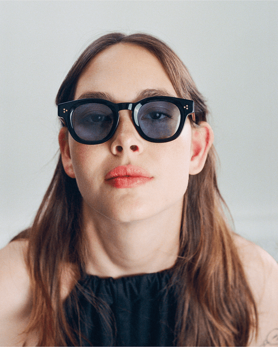 Woman wearing Coco black round sunglasses with light blue lenses
