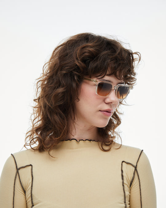 Woman wearing Pepino clear rectangle sunglasses with gradient orange-to-blue lenses, look 2