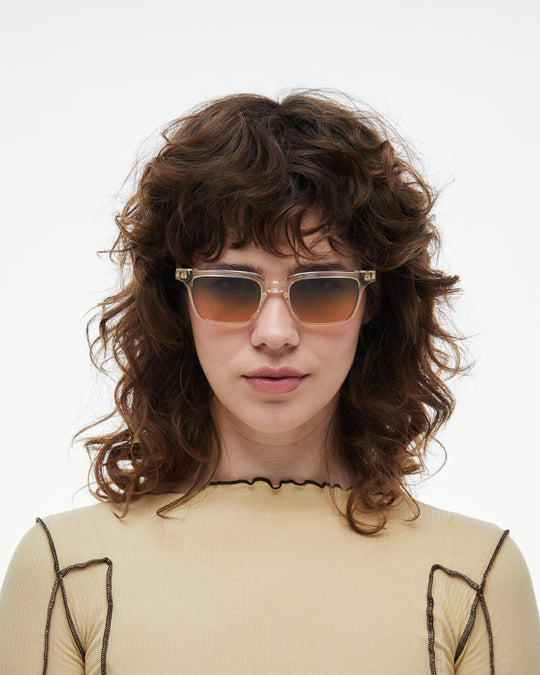 Woman wearing Pepino clear rectangle sunglasses with gradient orange-to-blue lenses
