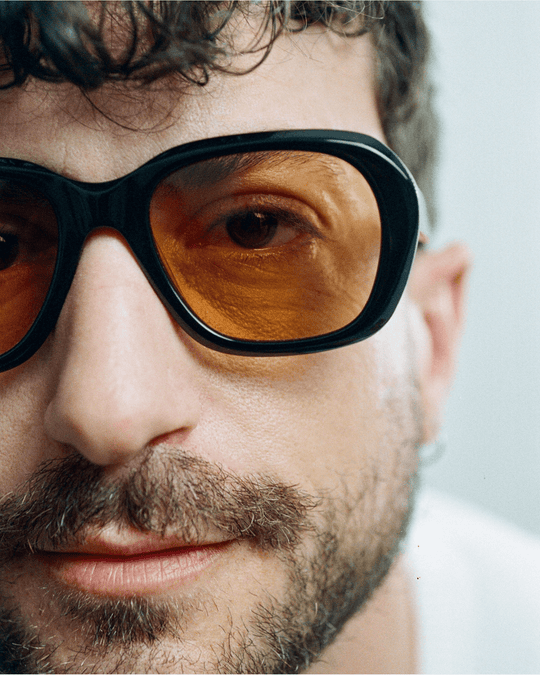Man wearing Tamar black round sunglasses with orange lenses