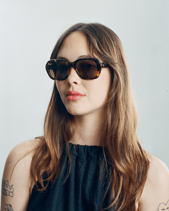 Woman wearing Tamar dark tortoise round sunglasses with brown lenses