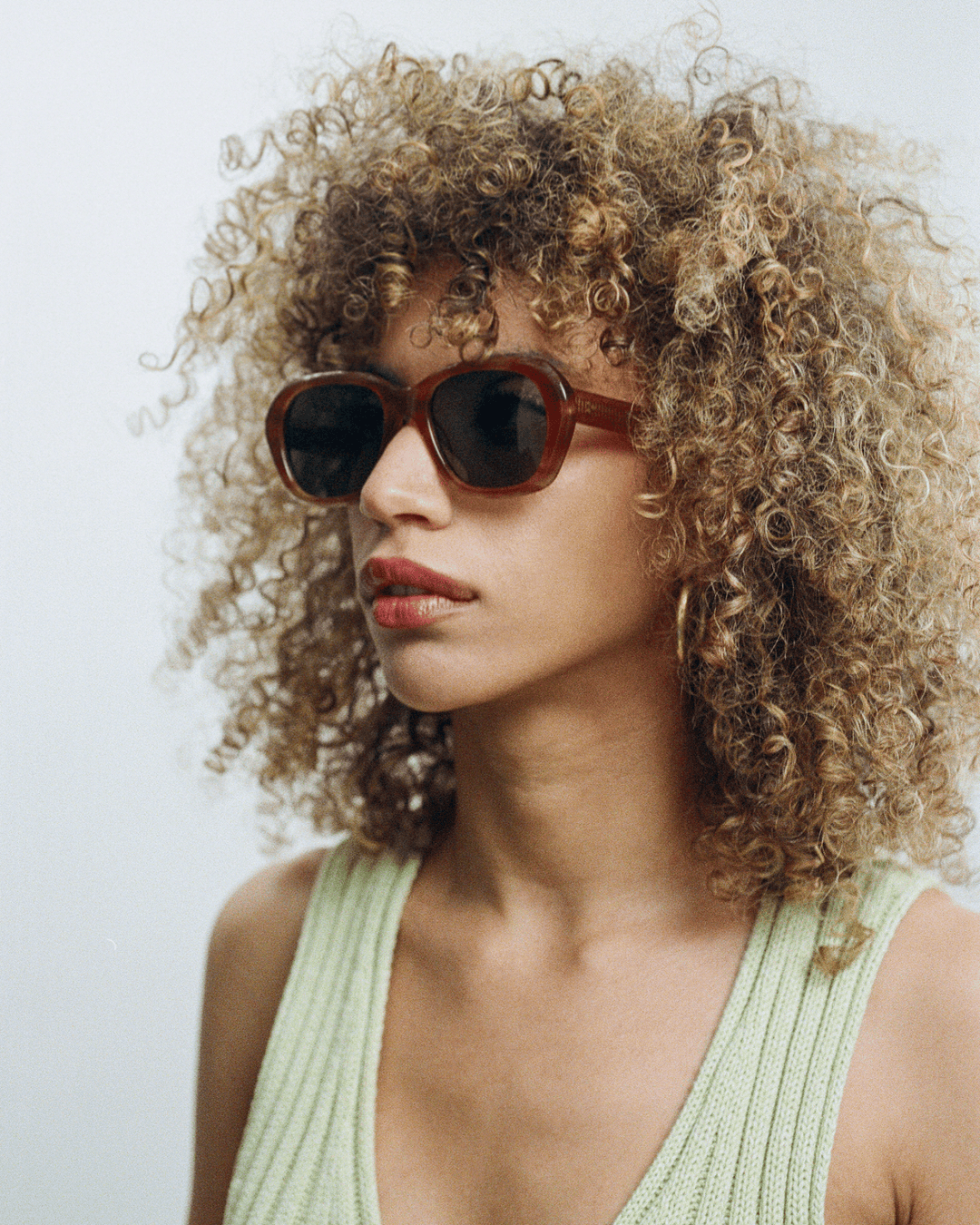 Woman wearing Tamar light brown round sunglasses with green lenses