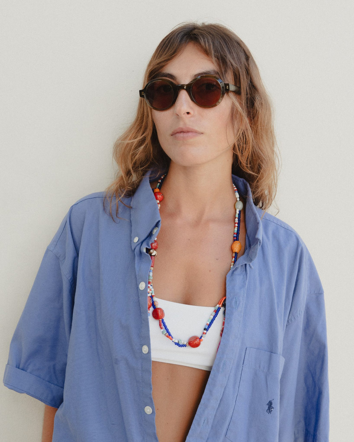 Woman wearing Umi brown round sunglasses with brown lenses and a blue shirt